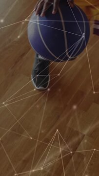 Vertical video: Teen tapping basketball training dribbling shifting ending near shoe under overlay