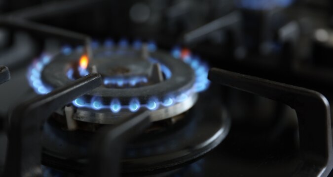 Gas burner with blue flame on stove, closeup. Space for text