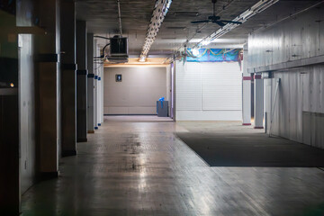 Abandoned retail space with long wooden floor, empty slatwall displays, old ceiling fans, and dim lighting, conveying an eerie sense of commercial decline and forgotten business. © Michael