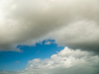 Obraz premium Blue cloudy sky. Nature background for design. Random shape. Calm cloudscape.
