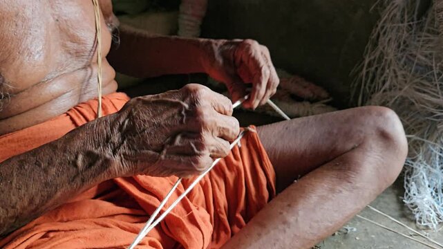 Elder Indian Brahmin making sacred thread janeyu by hand. Traditional Hindu ritual craft showing cultural heritage, spirituality, and authentic lifestyle.
