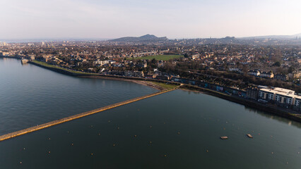 Naklejka premium Panoramic view of traditional stone residential buildings in Granton district, Edinburgh. The scene features authentic Scottish architecture near the coastline of the Firth of Forth with a local beach