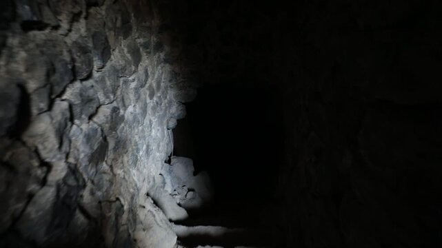  Moving slowly up a narrow, dark, and uneven stone staircase. The point of view approaches a bright arched exit, eventually stepping out into an overwhelmingly bright white light.