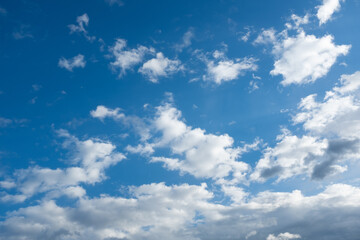 Obraz premium Blue sky with white clouds background, bright sunny weather, minimal nature scene, soft cloudscape, clean atmosphere, natural sky texture with copy space