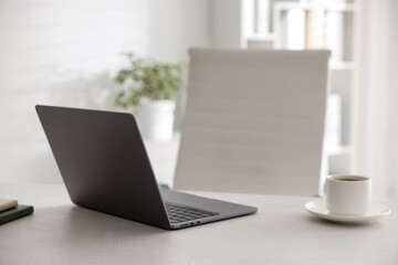 Fototapeta premium Stylish workplace with laptop and cup of drink on white desk indoors
