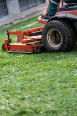 Obraz premium Close up of mower deck and wheel cutting fresh grass