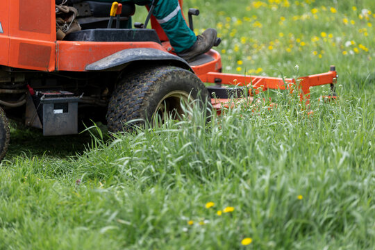 Commercial mower approaching overgrown lawn with wild grass