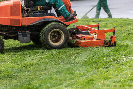 Commercial mower working on wet lawn during rainy day maintenance