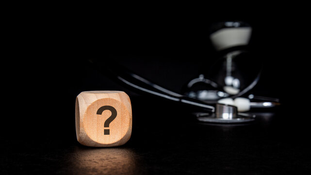 Medical uncertainty concept with question mark on wooden block and stethoscope. Healthcare diagnosis, time and health insurance questions.