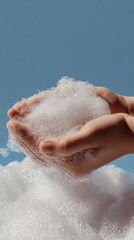 Fototapeta premium Close-Up of Hands Holding Foam Bubbles Against a Blue Background Emphasizing Hygiene and Cleanliness in a Vertical Orientation