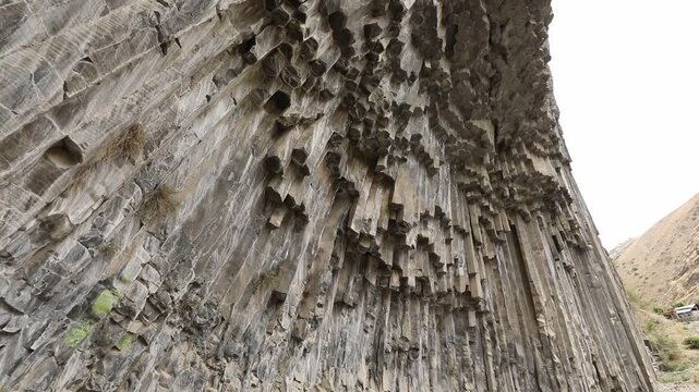 A breathtaking view of a massive cliff face composed of unique, vertical hexagonal basalt rock columns. This stunning natural geological formation looks like a giant, ancient stone organ.