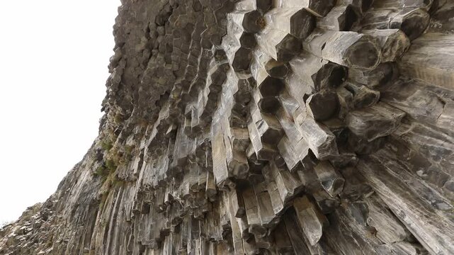 A breathtaking view of a massive cliff face composed of unique, vertical hexagonal basalt rock columns. This stunning natural geological formation looks like a giant, ancient stone organ.