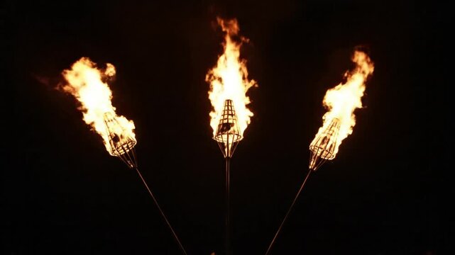 Three decorative flaming torches burning brightly against a completely dark night sky backdrop.
