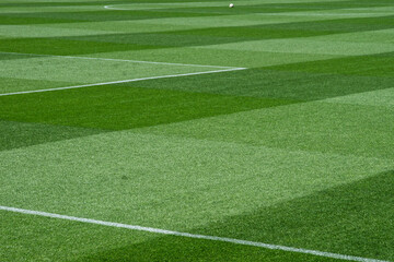 Obraz premium Well-Maintained Football Stadium Pitch with Striped Grass Under Clear Blue Sky