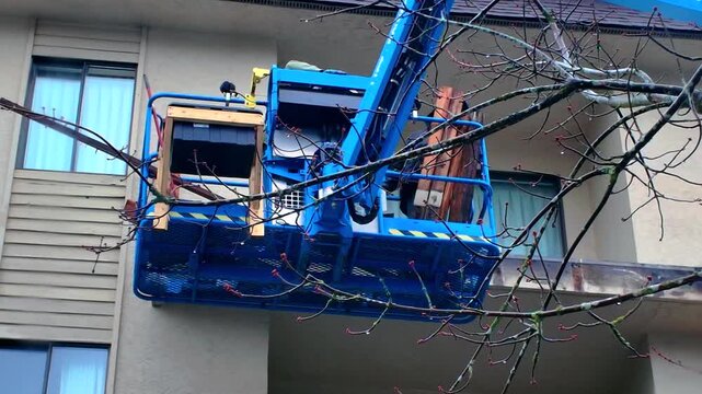 Blue aerial work platform boom lift at residential building exterior