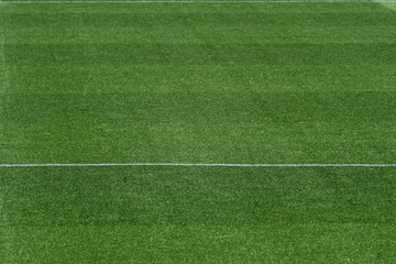 Obraz premium Well-Maintained Football Stadium Pitch with Striped Grass Under Clear Blue Sky