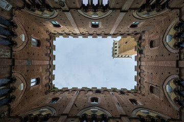 Obraz premium Medieval Courtyard Scene. Ancient Siena Tower Framed Beautifully. Charming Medieval Setting Showcasing Terracotta Tones And Architectural Details