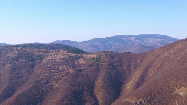 Cinematic 4K aerial view over dense pine forest and mountain peaks of Igman