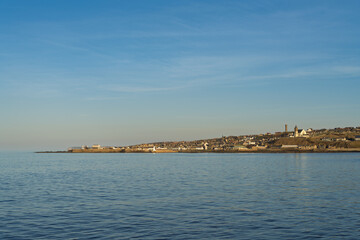 Fototapeta premium Macduff coastal town in Aberdeenshire Scotland seen across the calm Sea from its neighbor Banff under a clear blue sky