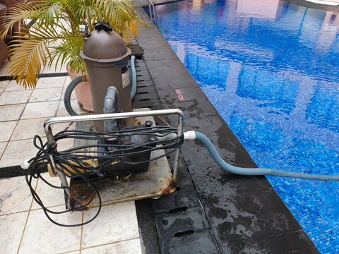 Operational swimming pool pump and filtration system diligently maintaining clean and clear water, positioned alongside a sparkling blue backyard pool for optimal aquatic enjoyment