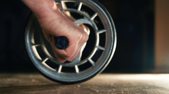 Man Hands Gripping Ab Roller Wheel on Gym Floor Ready to Exercise | Close-Up Shot of Core Workout Equipment | Dark Dramatic Lighting Fitness Training