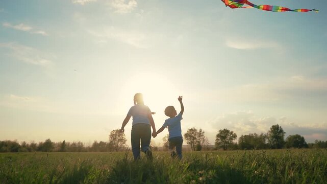 Mother and son flying kite. Group of children are holding kite together. Girl is playing with a kite and a boy is running. A mother and her son are flying a kite lifestyle.