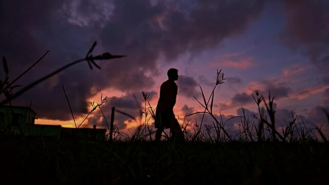 Silhouette of a cricket player playing a shot during dramatic sunset in India. Slow motion sports scene with golden sky, outdoor field, and action moment, ideal for cricket, sports themes.