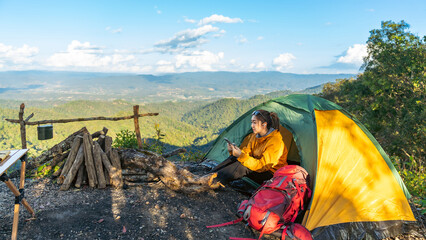 Naklejka premium Asian woman backpacker travel nature hiking and camping on mountain peak, sitting at campsite using internet on smartphone, outdoor adventure active lifestyle and telecommunication online technology