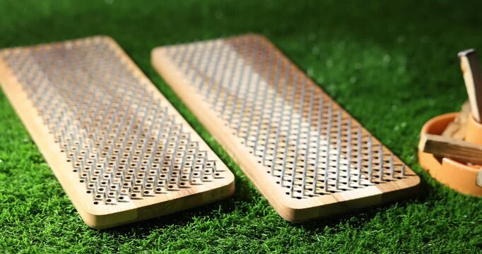 Standing on nails. Two Sadhu boards and Palo Santo sticks on green grass, closeup. Camera moving right