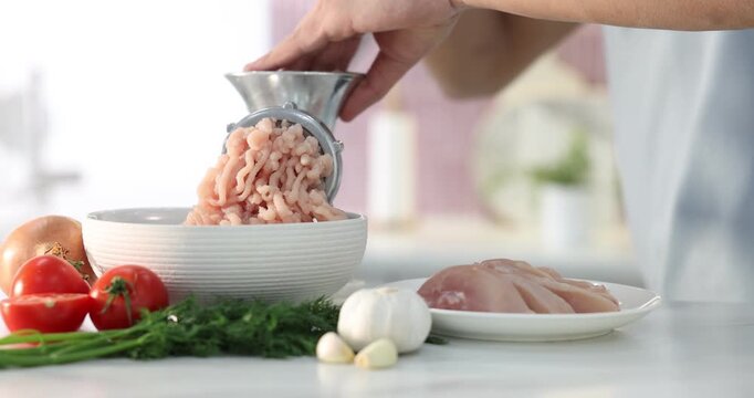 Man making minced meat with grinder at white table indoors, closeup