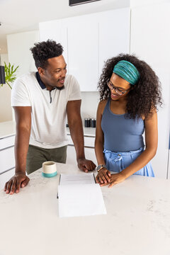 African American couple leaning on light countertop reviewing papers, two-tone mug nearby