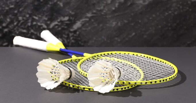 Shuttlecocks falling onto badminton rackets on grey table, closeup