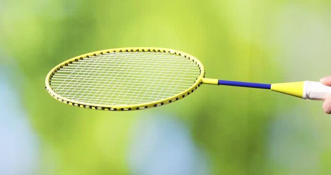 Woman with badminton racket and shuttlecock against blurred green background, closeup