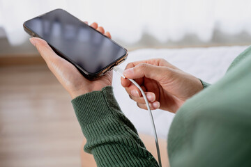 Close-up of woman hands plugging USB cable into smartphone. Symbolizing battery charging, power...