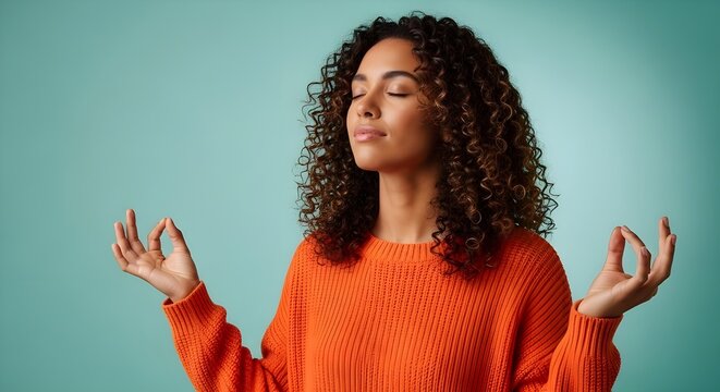 Una mujer afroamericana consciente y pac&iacute;fica medita en el interior, mantiene las manos en gesto mudra, tiene los ojos cerrados, intenta relajarse despu&eacute;s de largas horas de trabajo, sostiene los dedo