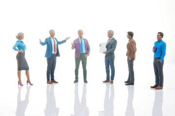 Fototapeta premium Miniature figures of people in discussion inside a bright room showcasing various poses and attire representing a meeting