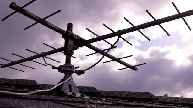 Weathered Television Antenna on a Shingled Roof, Cloudy Skies in the Background, Day Exterior View
