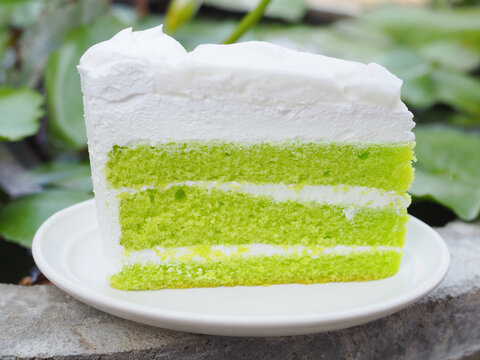 A pandan cake topped with young coconut custard is placed on a plate. It has a vibrant green color, looks appetizing, and tastes wonderfully sweet and soft.