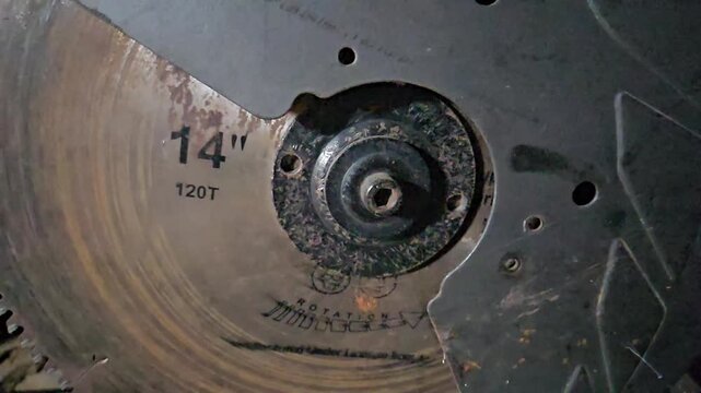 Close-up of a circular saw blade cutting through metal in an industrial workshop. The scene captures precision machining, sharp rotating blade, and manufacturing process.