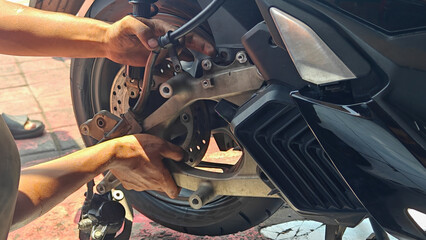 Close Up of Mechanic Repairing Motorcycle Rear Brake System and Suspension © Made