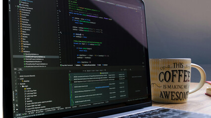 Programmer coding on laptop with coffee mug and motivational quote in dark workspace © Imran