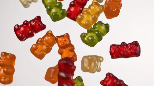 Colorful gummy bears candies falling on white background
