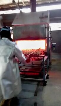 African smelter wearing aluminized fireproof gear, face shield checking the process of melting gold in industrial furnace, foundry. Stack of gold bars on fire. Gold refining process with intense heat 