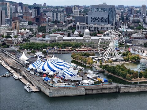 24th of August 2025 drone flight above the Cirque du Soleil blue-white tent at Montreal Old Port with city skyline in background. g.