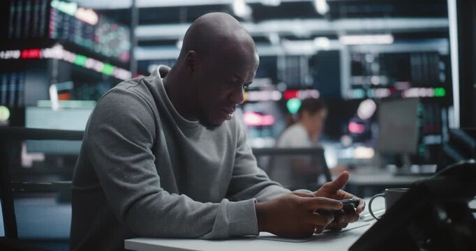 Focused African American Male Trader Executing Urgent Order Via Smartphone. Man Uses Mobile App Execute Critical Trade or Monitor Asset Prices. Speed Mobile Technology in Modern Financial Markets.