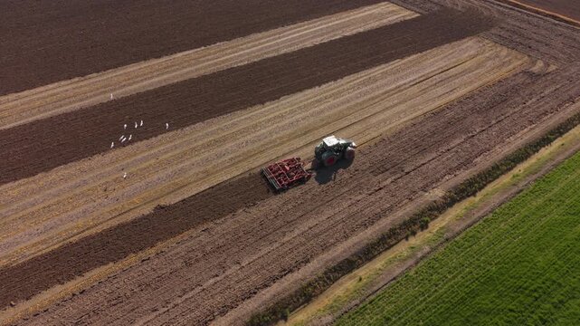 Tractor Tilling Agricultural Land: A solitary tractor carves precise rows into the fertile earth of farmland, showcasing the essential role of technology in modern agriculture.