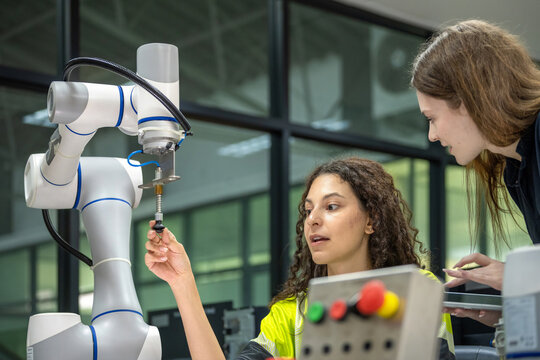 Robotics Education: Female Engineers with a Laptop, Focused on a Robotic Arm Female Engineers Working on the Programming of a Robotic System Two Women Collaborating on a Robotics Engineering Project