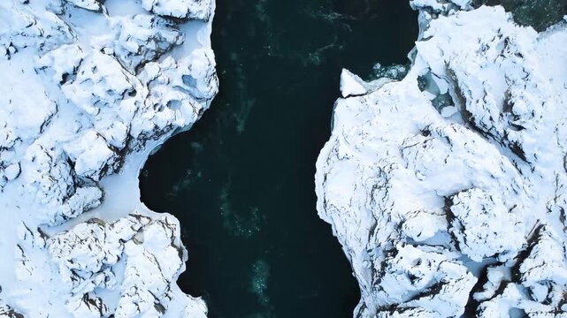 Overhead Icy Gorge River Rocks Snow Showcasing Rugged Snowblanketed Cliffs Framing Dark Rushing Water, Sharp Textures And Contrast, Windswept Ridges, Cinematic Adventure Mood And Geological Detail