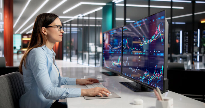 Skilled Woman Broker Analyzing Stock Market Data On Multiple Screens