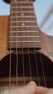 Vertical video. Guitar Playing in Close-Up, String Vibrations with Wave Motions in Short Camera Exposure.